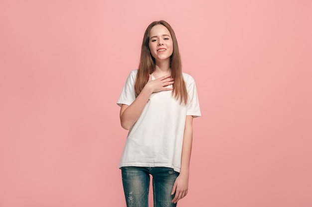 Das glückliche jugendlich Mädchen, das gegen rosa Wand steht und lächelt