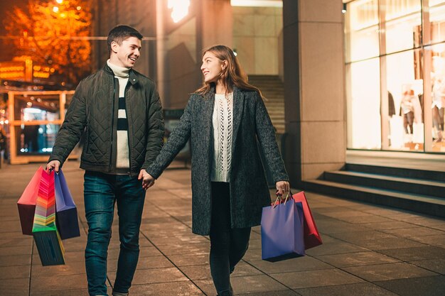 Das glückliche Paar mit Einkaufstüten genießt die Nacht in der Stadt
