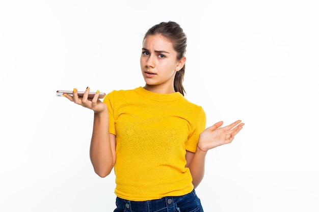 Das junge glückliche jugendlich Mädchen ruft mit einem auf Weiß isolierten Mobiltelefon an