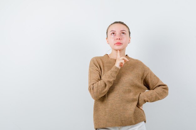 Das junge Mädchen denkt an etwas auf weißem Hintergrund