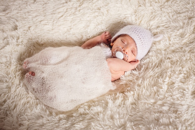 Das kleine Baby hat einen Dummy und liegt auf dem Bett