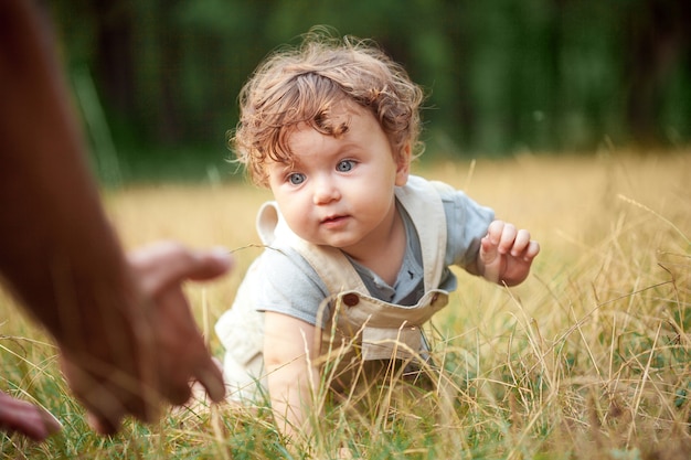 Das kleine Baby oder das einjährige Kind auf dem Gras im sonnigen Sommertag