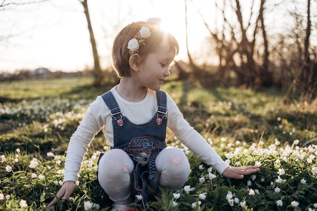 Das kleine mädchen, das nahe blumen sitzt