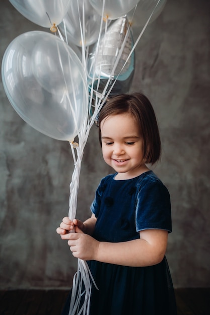 Das kleine Mädchen hält Ballons im Zimmer