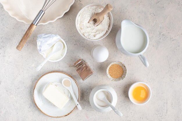 Das Konzept des Backens zu Hause Zutaten für die Herstellung von Teigkuchen, Cupcakes, Eiern, Mehl, Butter, Zimt, Milchzucker auf hellem Hintergrund