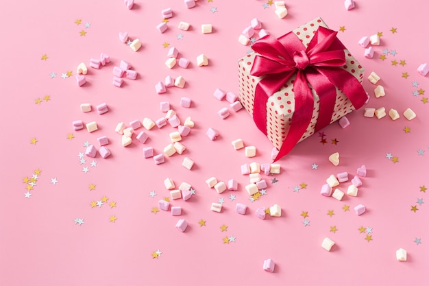 Das Konzept des Valentinstags. Geschenkbox mit roter Schleife an rosa Wand.
