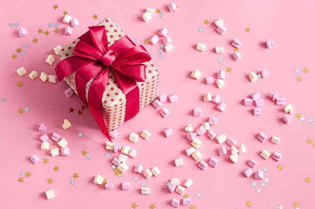 Das Konzept des Valentinstags. Geschenkbox mit roter Schleife auf rosa.