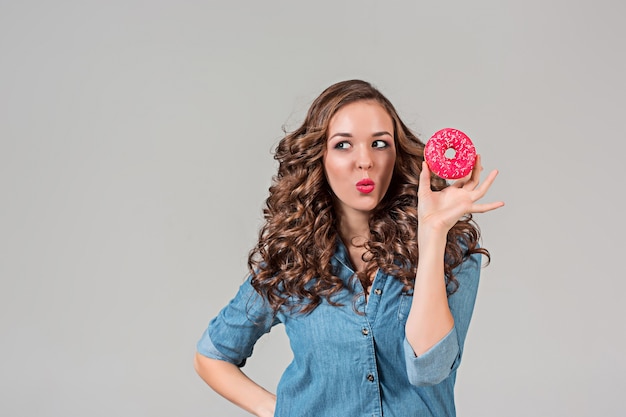 Das lächelnde Mädchen mit rundem Kuchen auf grauer Wand. Lange Haare.