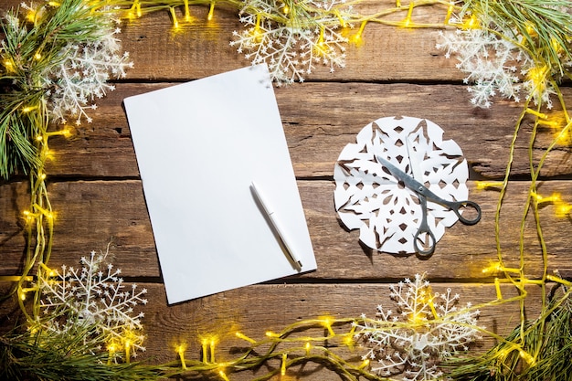 Das leere Blatt Papier auf dem Holztisch mit einem Stift und Weihnachtsschmuck.