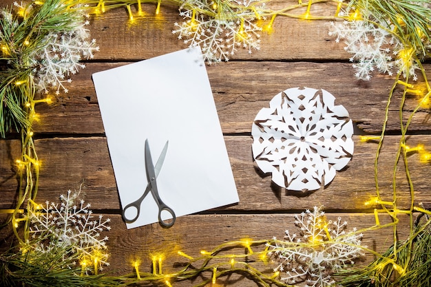 Kostenloses Foto das leere blatt papier auf dem holztisch mit einer schere und weihnachtsschmuck.