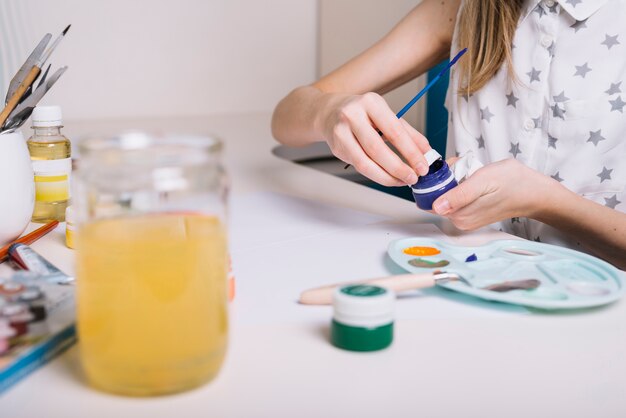 Das Mädchen, das blaue Gouache öffnet, kann bei Tisch