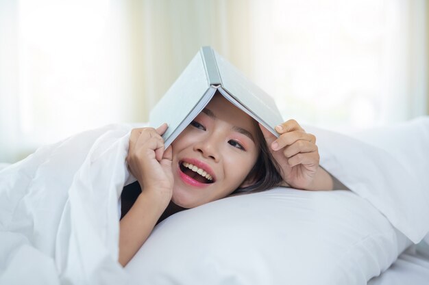 Das Mädchen im Bett liegend, Musik hörend und Bücher lesend.