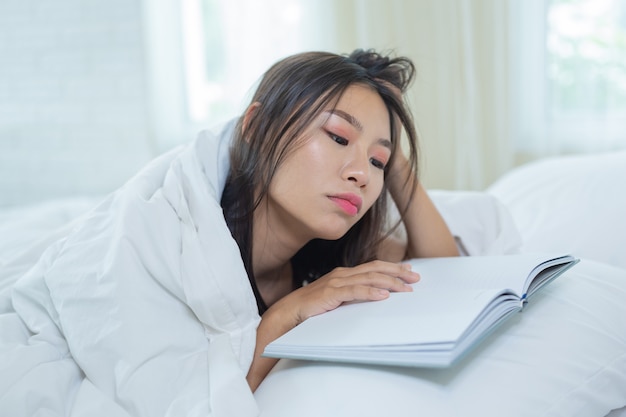 Das Mädchen im Bett liegend, Musik hörend und Bücher lesend.