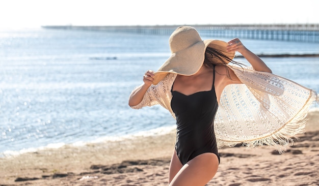 Das Mädchen in einem Badeanzug bedeckte ihr Gesicht mit einem großen Hut. Sommerferienkonzept auf See.