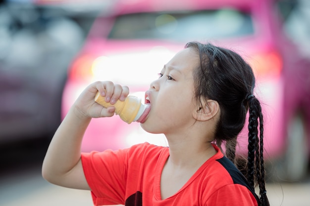 Das Mädchen isst Eis auf dem Parkplatz im Freien.