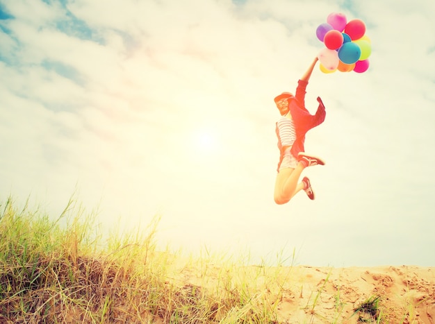 Das Mädchen springend in den Strand mit Luftballons