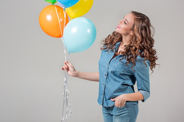 Das mädchen und ein bündel bunter luftballons auf grau