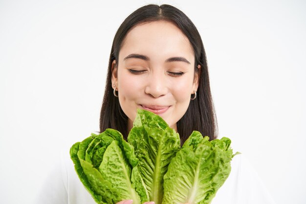 Das Nahaufnahmeporträt einer glücklichen koreanischen Frau zeigt ihr Gesicht mit Salat, die Kohl isst und Gemüse mag