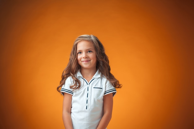 Das niedliche fröhliche kleine Mädchen auf orange Hintergrund