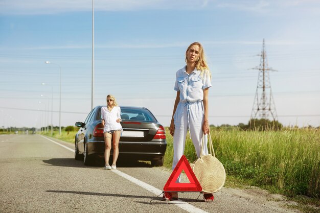 Das Paar der jungen Lesben, das an sonnigem Tag auf dem Auto Urlaub macht