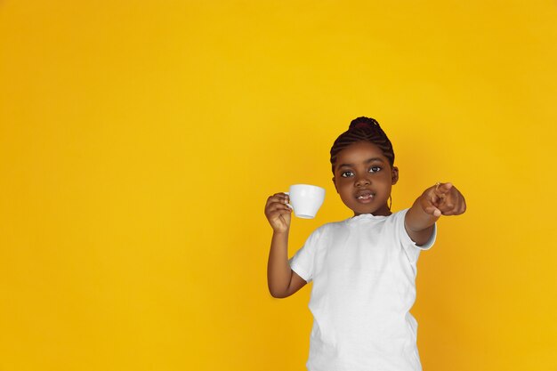 Das Porträt des kleinen afroamerikanischen Mädchens lokalisiert auf gelbem Studio
