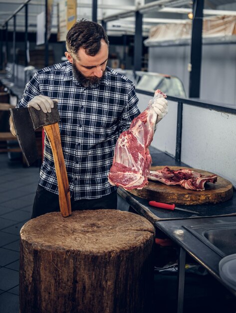 Das Porträt eines bärtigen Fleischmannes in einem Fleecehemd hält eine Axt und frisch geschnittenes Fleisch.