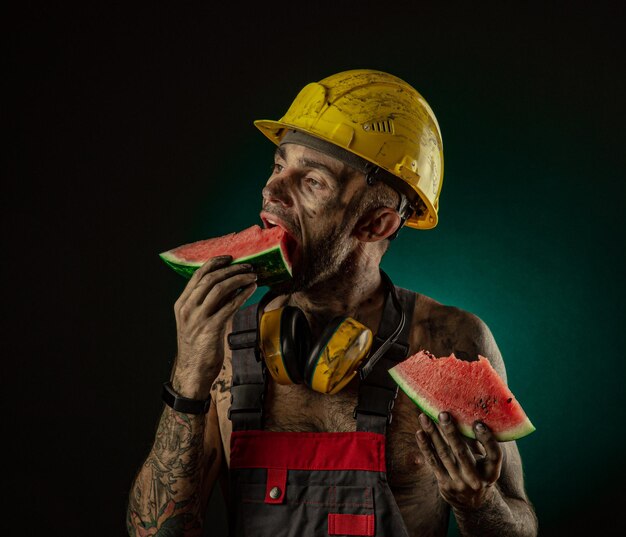 Das porträt eines glücklich lächelnden bergmanns, der wassermelone zum mittagessen isst