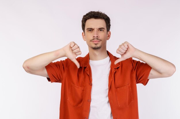 Das Porträt eines jungen Mannes zeigt Anzeichen von Abneigung mit negativem Gesichtsausdruck und Missbilligung auf isoliertem Hintergrund