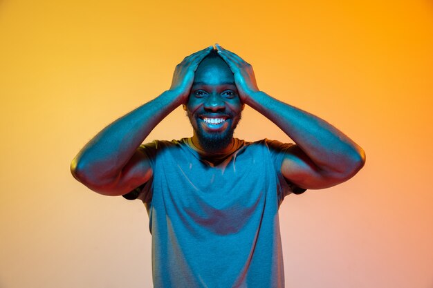 Das Retro-Wellen- oder Synth-Wellenporträt eines jungen glücklichen ernsten afrikanischen Mannes im Studio.