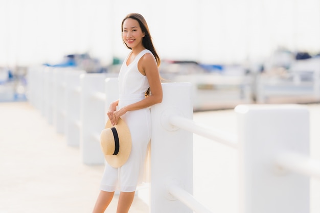 Das schöne junge asiatische Frauenfreizeitlächeln des Porträts, das glücklich ist, entspannen sich um Yachthafen