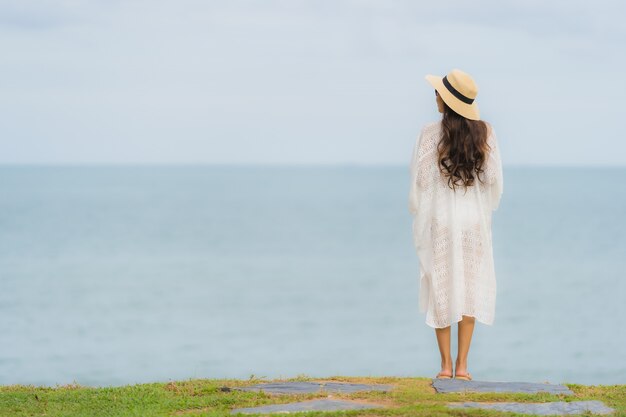 Das schöne junge asiatische glückliche Frauenlächeln des Porträts entspannen sich auf dem Strandseeozean