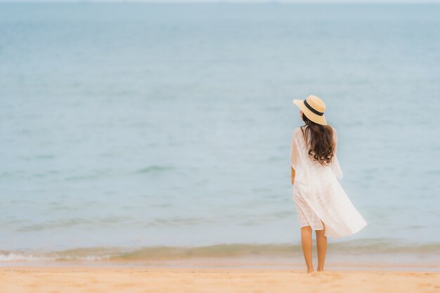 Das schöne junge asiatische glückliche Frauenlächeln des Porträts entspannen sich auf dem Strandseeozean