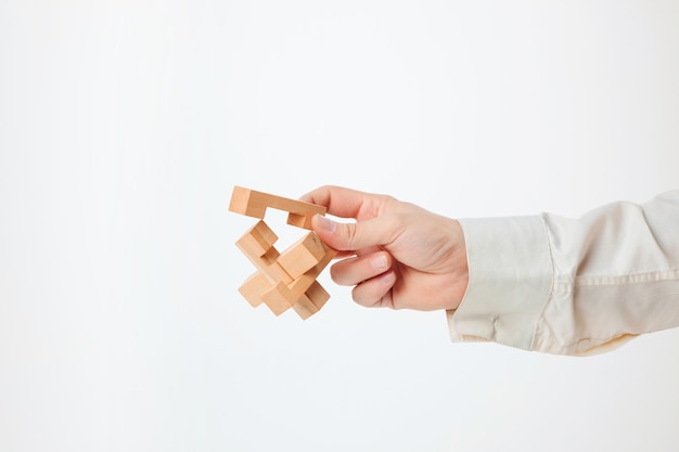 Das Spielzeug-Holzpuzzle in der Hand lokalisiert auf weißer Wand