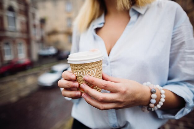 Das stilvolle Mädchen hält eine Tasse Kaffee