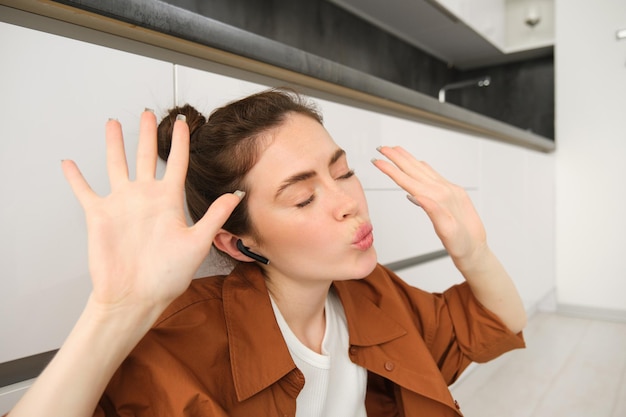 Kostenloses Foto das tanzende mädchen sitzt auf dem küchenboden und bewegt sich im rhythmus und genießt die klangqualität im wlan