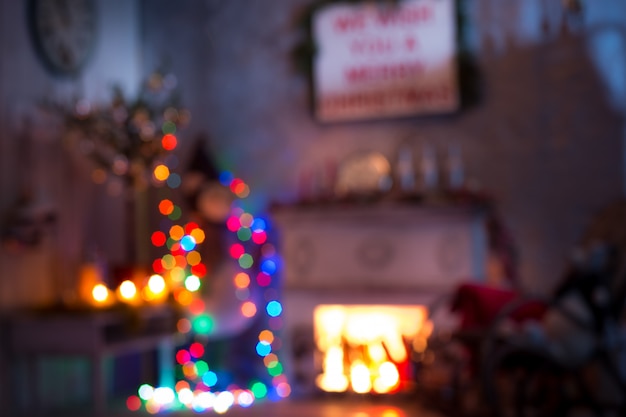 Das verschwommene Weihnachts- und Neujahrsinterieur des Wohnzimmers. Alter Schaukelstuhl am geschmückten Baum- und Kaminraum.