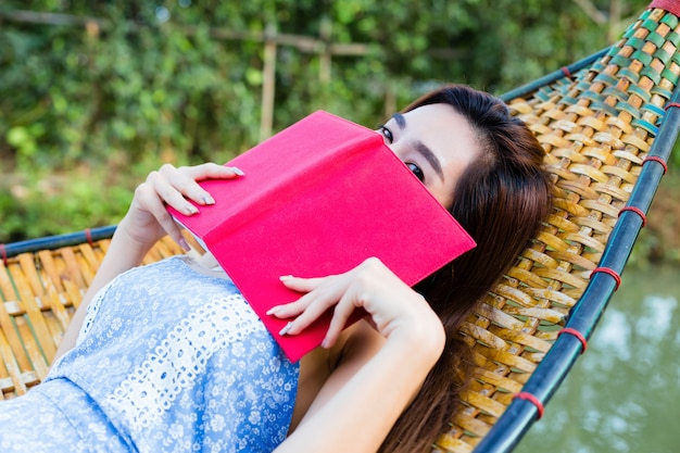 Das weibliche Lügen des Jugendlichen auf Bambushängematte und las ein Buch