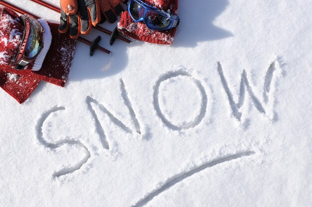 Das Wort Schnee mit Ski-Kleidung und Ausrüstung
