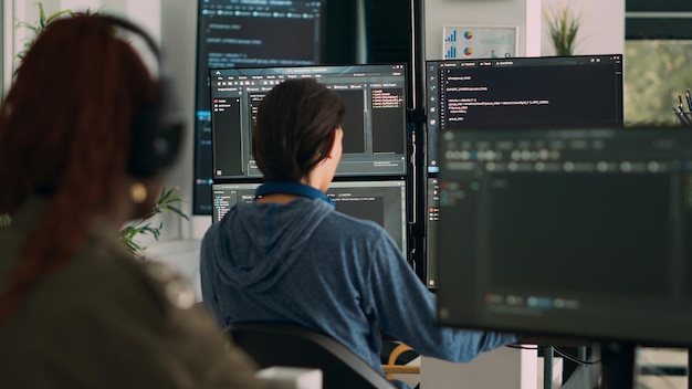 Datenbankprogrammierer, der Code auf Terminalfenster schreibt und dabei mehrere Monitore im Büro der Agentur verwendet. Systemsoftwareentwickler, der Datenbankinformationen eingibt und Big-Data-Skripts berechnet.