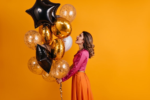 Debonair frau, die partyballons betrachtet