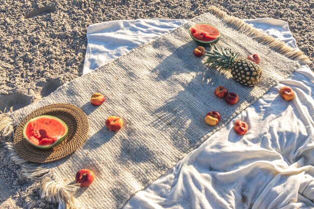 Decke mit Früchten auf Sandstrand-Picknick-Konzept