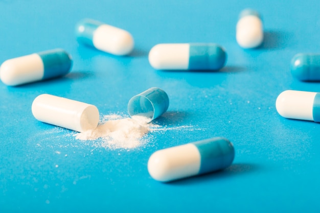 Defekte weiße antibiotische Kapsel auf blauem Hintergrund