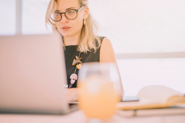 Defocused Glas Saft vor der Geschäftsfrau, die Laptop verwendet