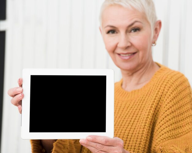 Defocused reife Frau, die Tablette in den Händen hält
