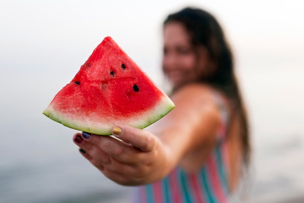 Defokussierte Frau im Wasser am Strand, der Wassermelone hält