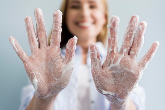 Defokussierte Frau zeigt ihre Hände mit Seife bedeckt