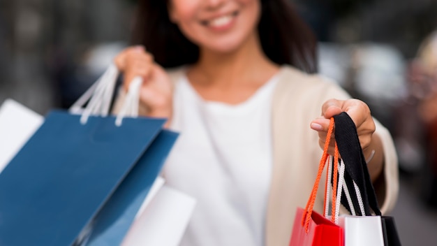Defokussierte Smiley-Frau, die Einkaufstaschen nach Verkaufssitzung hält