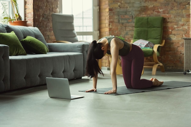 Dehnen. Sportliche schöne junge Frau, die zu Hause Yoga-Asanas wie Profi praktiziert.