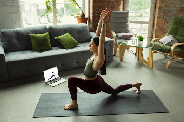 Dehnen. Sportliche schöne junge Frau, die zu Hause Yoga-Asanas wie Profi praktiziert.