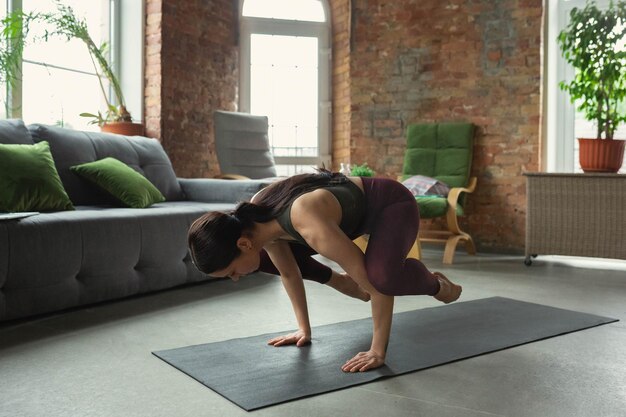 Dehnen. Sportliche schöne junge Frau, die zu Hause Yoga-Asanas wie Profi praktiziert.